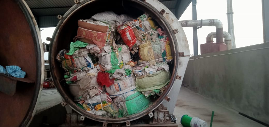 Baled plastic waste feedstock loaded into IMI thermal conversion reactor